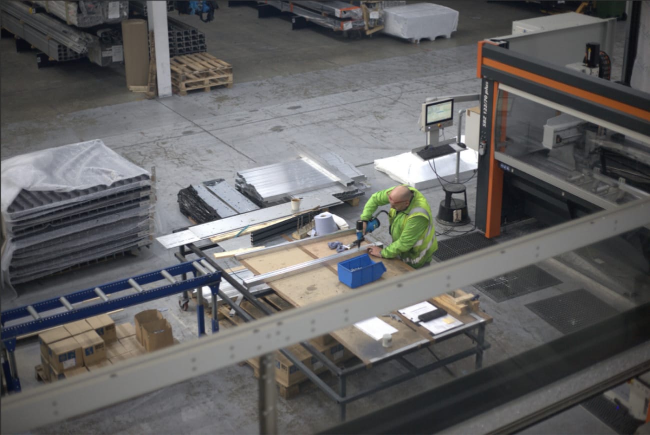 Overhead view of AliDeck's manufacturing facility with worker assembling aluminium decking components